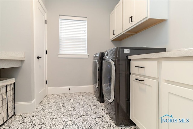 washroom featuring cabinets, light tile patterned floors, and washer and clothes dryer