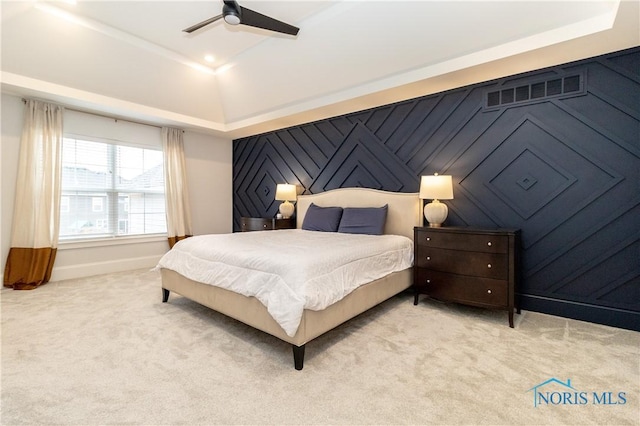 bedroom with light carpet, ceiling fan, and a tray ceiling