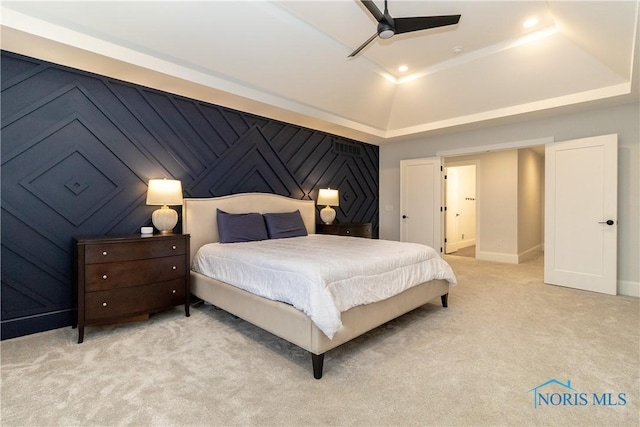 bedroom featuring a raised ceiling, light colored carpet, and ceiling fan