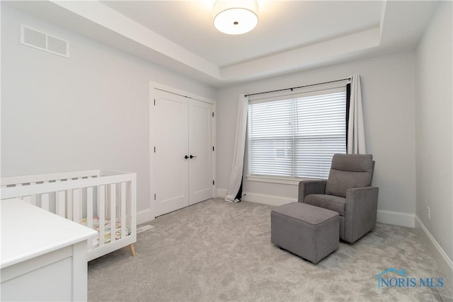 carpeted bedroom featuring a closet and a tray ceiling