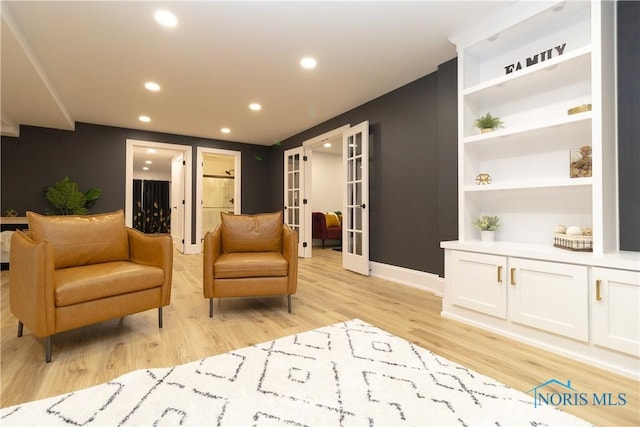 sitting room featuring built in features, light wood-type flooring, and french doors