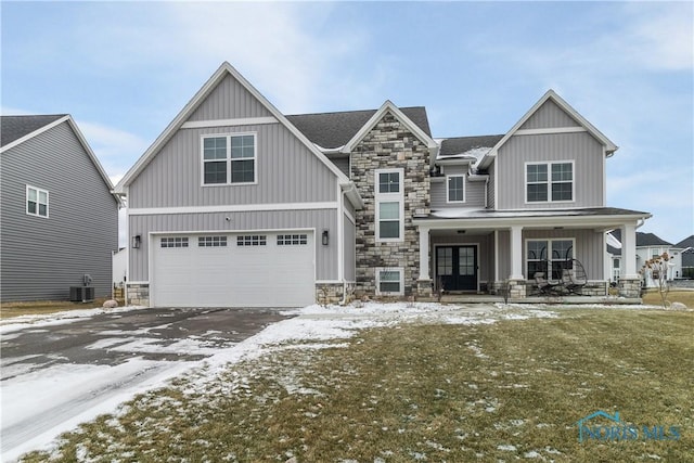 craftsman-style house with a garage, a yard, central AC unit, and covered porch