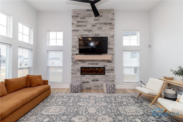 living room featuring a towering ceiling, a stone fireplace, and hardwood / wood-style floors