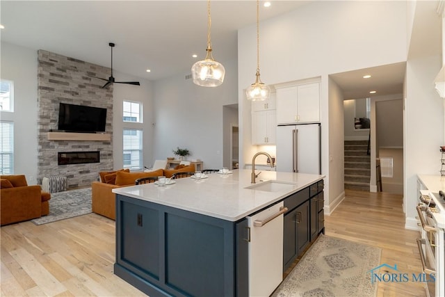 kitchen with sink, white cabinetry, hanging light fixtures, premium appliances, and a fireplace