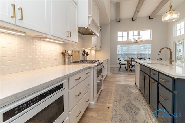 kitchen with pendant lighting, beamed ceiling, sink, white cabinets, and range with two ovens