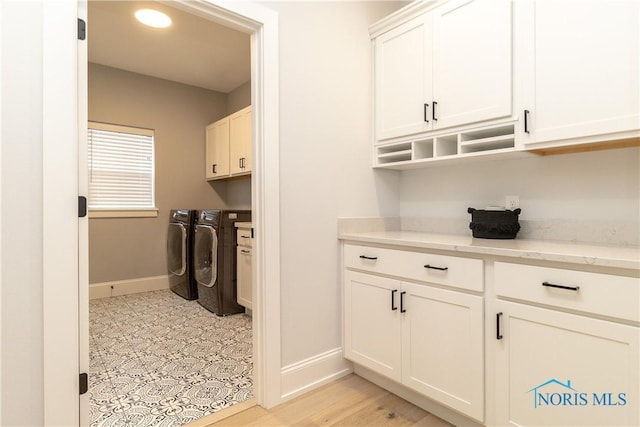 clothes washing area featuring cabinets and washer and dryer