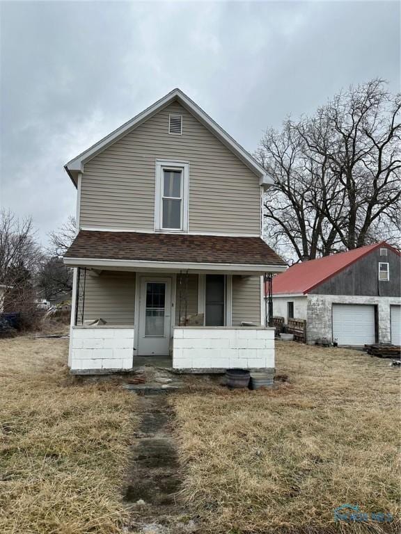 view of front of home with a garage, an outdoor structure, a front lawn, and a porch