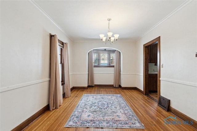 unfurnished dining area with visible vents, arched walkways, light wood finished floors, and a chandelier