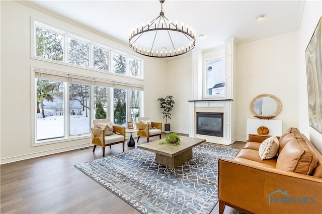 living room with dark hardwood / wood-style flooring, a large fireplace, crown molding, and a chandelier