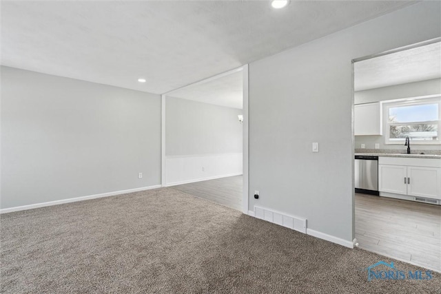 unfurnished room with recessed lighting, visible vents, carpet flooring, a sink, and baseboards