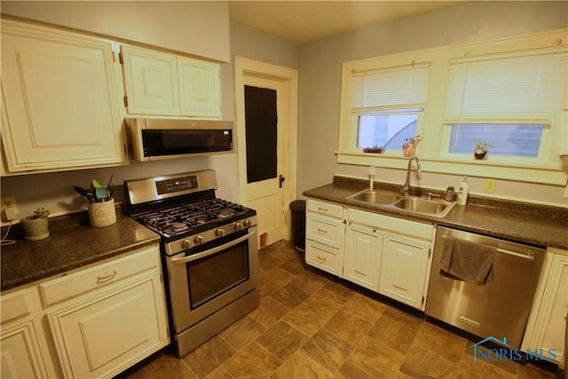 kitchen with stainless steel appliances, cream cabinets, and sink