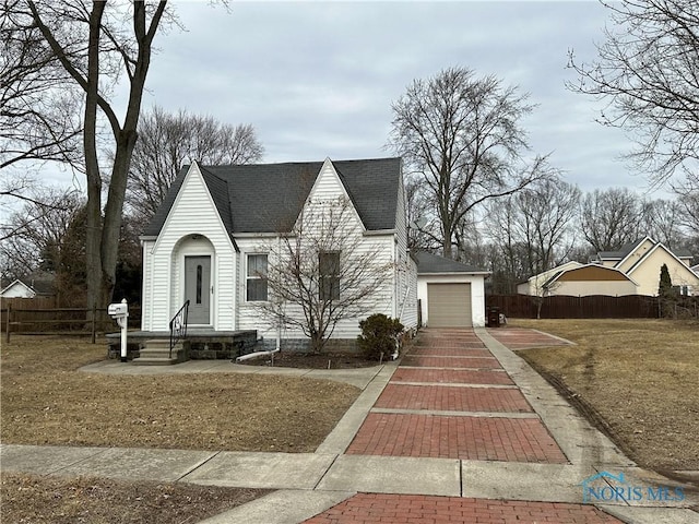 view of front of property featuring a garage, roof with shingles, and fence