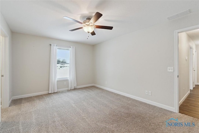 carpeted empty room with ceiling fan and baseboards