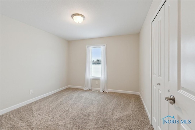 spare room with light carpet and baseboards