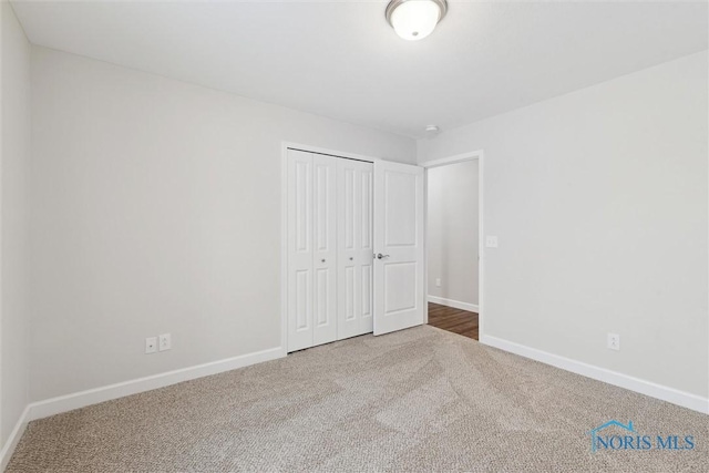 unfurnished bedroom with carpet floors, a closet, and baseboards