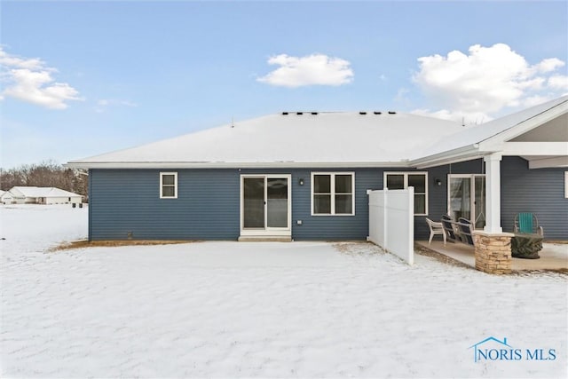 snow covered rear of property featuring a patio area