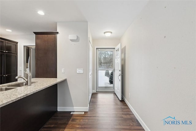 doorway with dark wood-style floors, recessed lighting, a sink, and baseboards