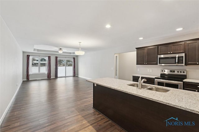 kitchen featuring dark brown cabinetry, a sink, appliances with stainless steel finishes, light stone countertops, and pendant lighting