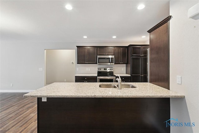 kitchen featuring light stone counters, stainless steel appliances, recessed lighting, dark brown cabinetry, and a sink