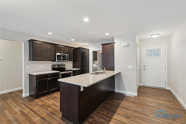 kitchen with dark wood-style floors, appliances with stainless steel finishes, a sink, and light stone counters