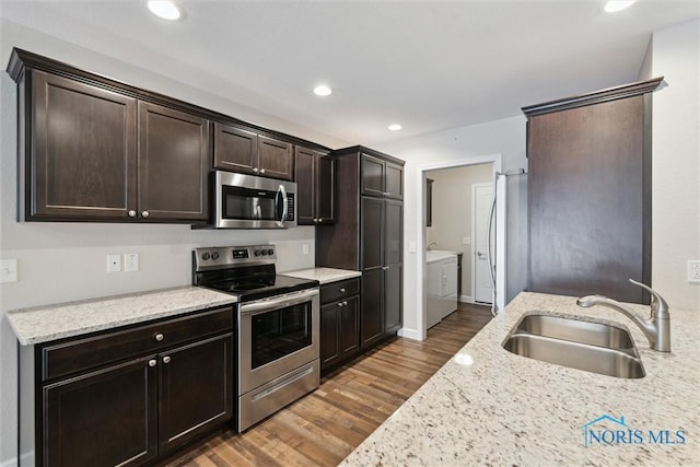 kitchen with light stone counters, a sink, dark brown cabinets, appliances with stainless steel finishes, and washing machine and clothes dryer