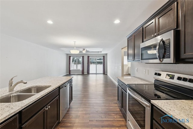 kitchen with dark brown cabinetry, light stone counters, dark wood-style flooring, stainless steel appliances, and a sink