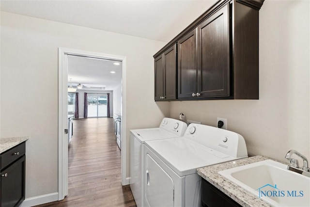 washroom featuring a sink, a ceiling fan, light wood-style floors, washer and dryer, and cabinet space