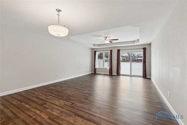 unfurnished room with a ceiling fan, a raised ceiling, baseboards, and dark wood-style flooring