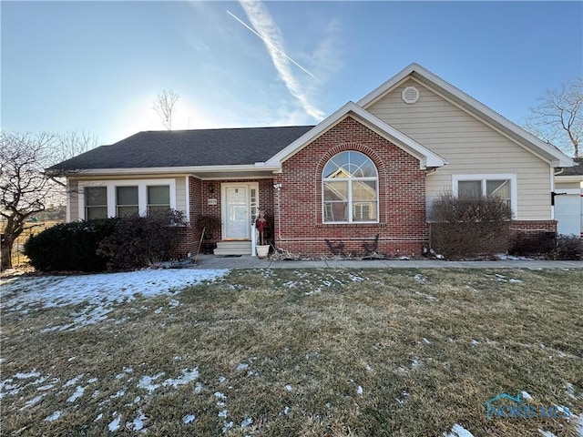 ranch-style house featuring a front yard, brick siding, and roof with shingles