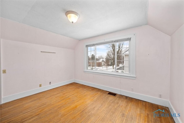 bonus room featuring vaulted ceiling, light hardwood / wood-style flooring, and a textured ceiling