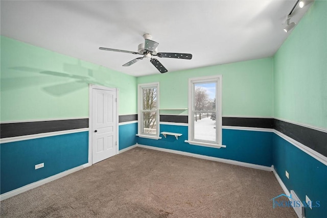 carpeted spare room with rail lighting and ceiling fan