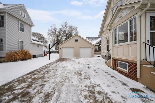 snow covered property with a garage and an outbuilding