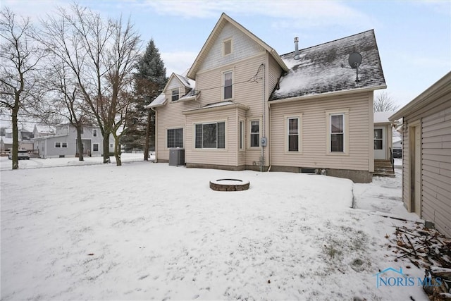 snow covered house with an outdoor fire pit and central air condition unit