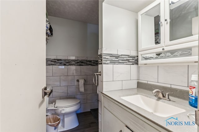 615 Lincolnshire Ln, Findlay, OH 45840 - bathroom with hardwood / wood-style flooring, tile walls, vanity, a textured ceiling, and toilet