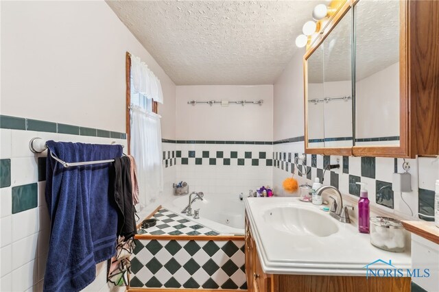 615 Lincolnshire Ln, Findlay, OH 45840 - bathroom featuring tiled tub, vanity, tile walls, and a textured ceiling