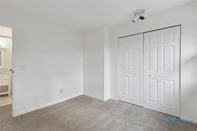 unfurnished bedroom featuring light colored carpet and a closet