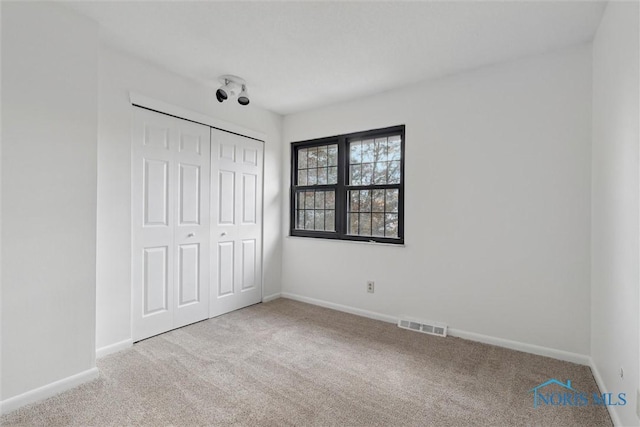 unfurnished bedroom featuring a closet and light carpet