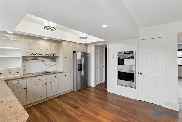 kitchen with appliances with stainless steel finishes, dark hardwood / wood-style flooring, decorative backsplash, and cream cabinetry