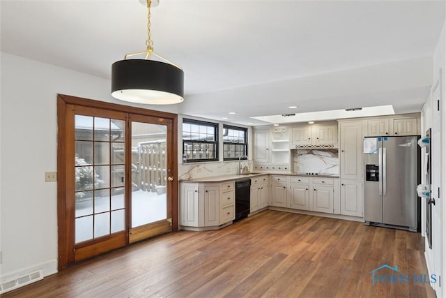 kitchen with hardwood / wood-style flooring, stainless steel fridge, black dishwasher, decorative backsplash, and decorative light fixtures