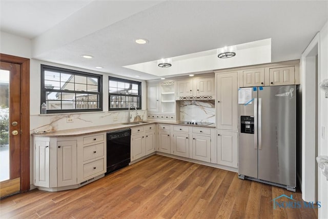 kitchen with sink, light hardwood / wood-style flooring, backsplash, and black appliances