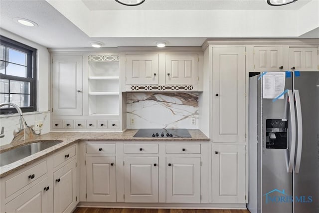 kitchen featuring sink, stainless steel fridge with ice dispenser, white cabinets, black electric stovetop, and backsplash