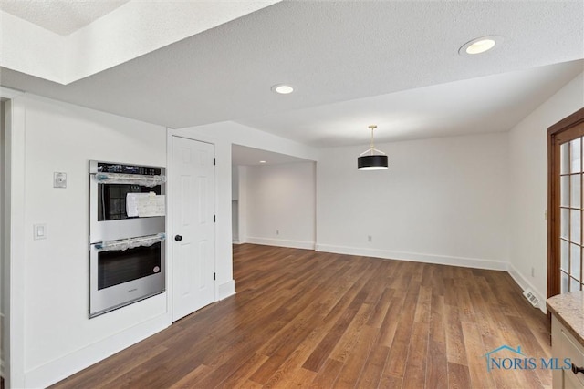 unfurnished living room with dark hardwood / wood-style floors and a textured ceiling