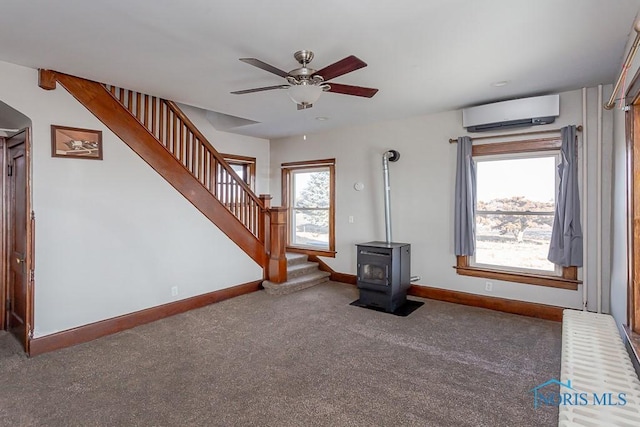 unfurnished living room with carpet floors, a wall mounted AC, a wood stove, baseboards, and stairs