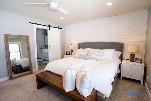 carpeted bedroom featuring ensuite bathroom, ceiling fan, and a barn door