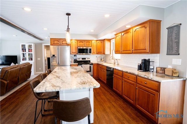 kitchen with sink, a center island, a kitchen breakfast bar, stainless steel appliances, and hanging light fixtures