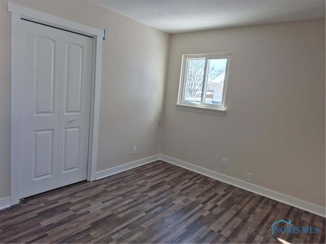 unfurnished bedroom featuring a closet and dark hardwood / wood-style floors