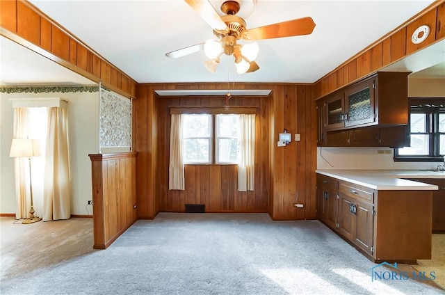 kitchen with ceiling fan, light carpet, and wooden walls