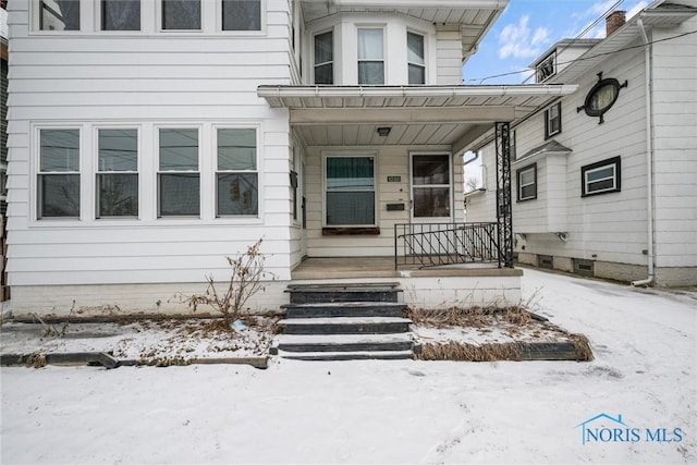 snow covered property entrance featuring covered porch