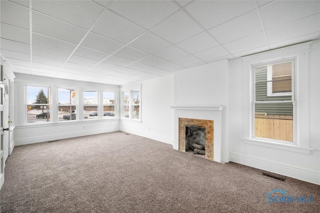 unfurnished living room featuring a fireplace, carpet flooring, and a paneled ceiling