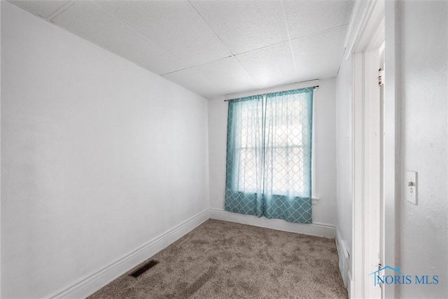 carpeted empty room with a paneled ceiling